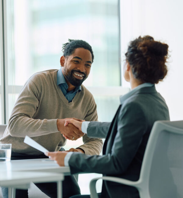 Happy black man shaking hands with his financial advisor in office.